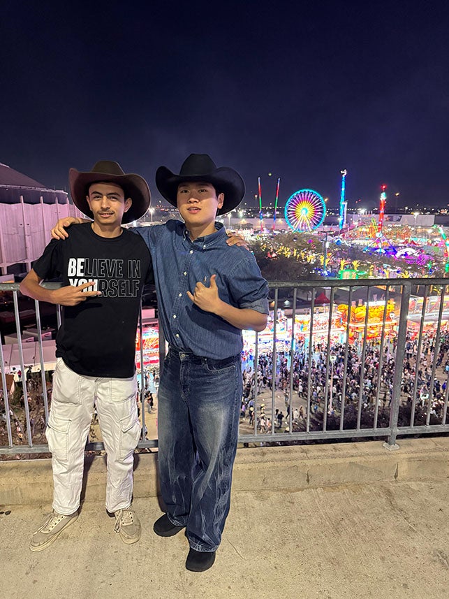 two male students posing in front of a rodeo carnival