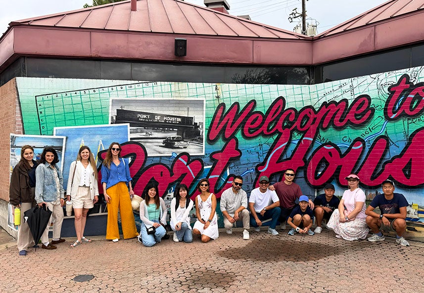 group of adults and small children standing in front of Welcome to Houston painting