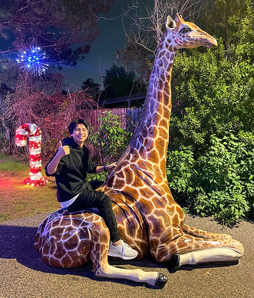 student riding giraffe statue at the Houston Zoo
