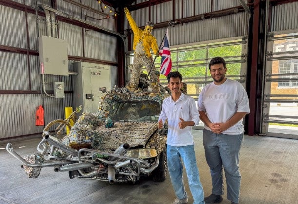 two Middle Eastern male college students standing with art car