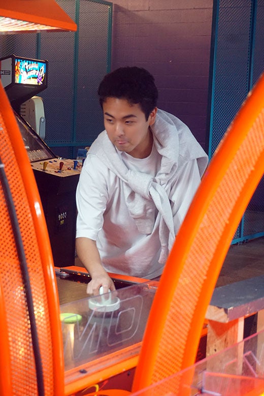 asian male playing air hockey at an arcade
