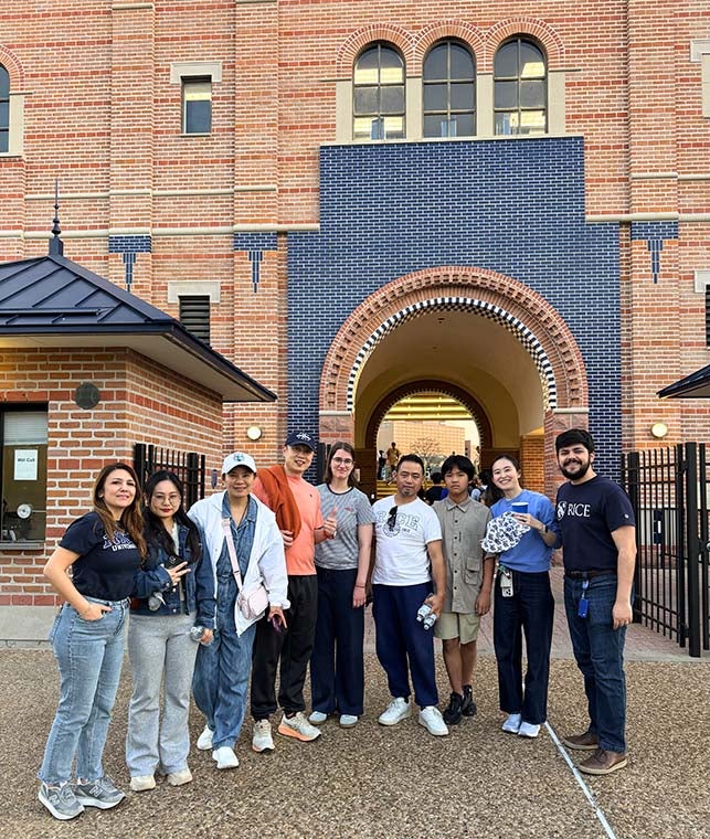 group of college-aged international students in front of baseball park