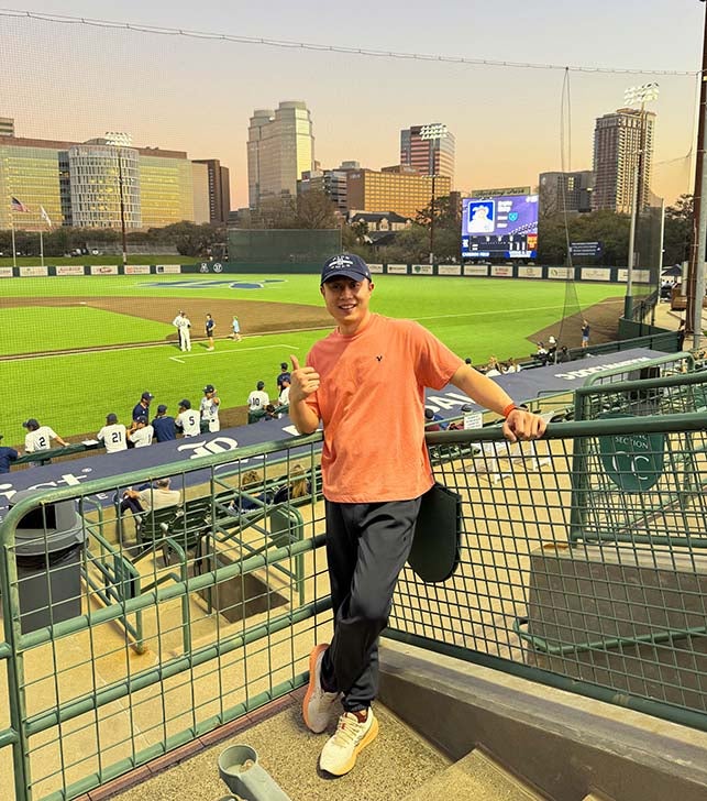 chinese man standing in front of a baseball field