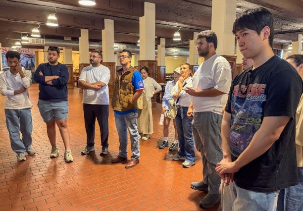 group of adults inside brewery listening to tour guide