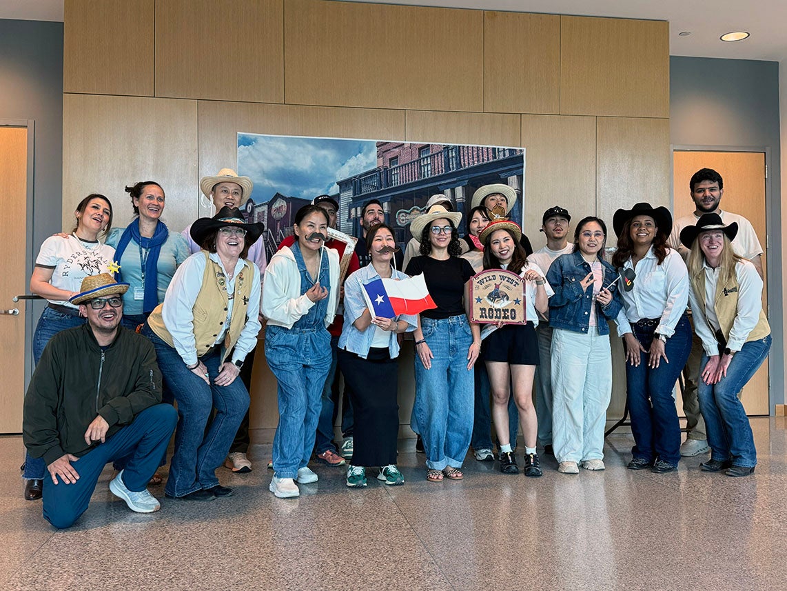 diverse group of adult students posing in front of a western scene in western wear