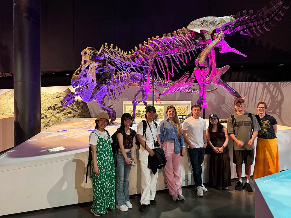 adults standing in front of dinosaur skeleton at science museum
