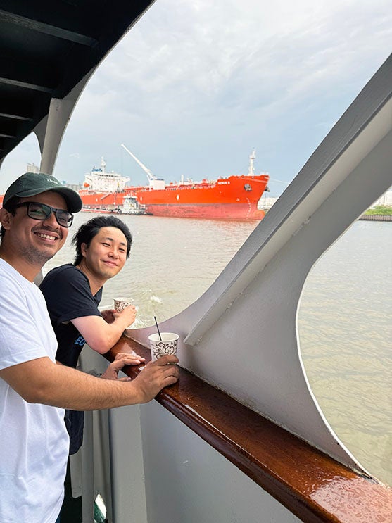 two adult men standing on the balcony of a boat