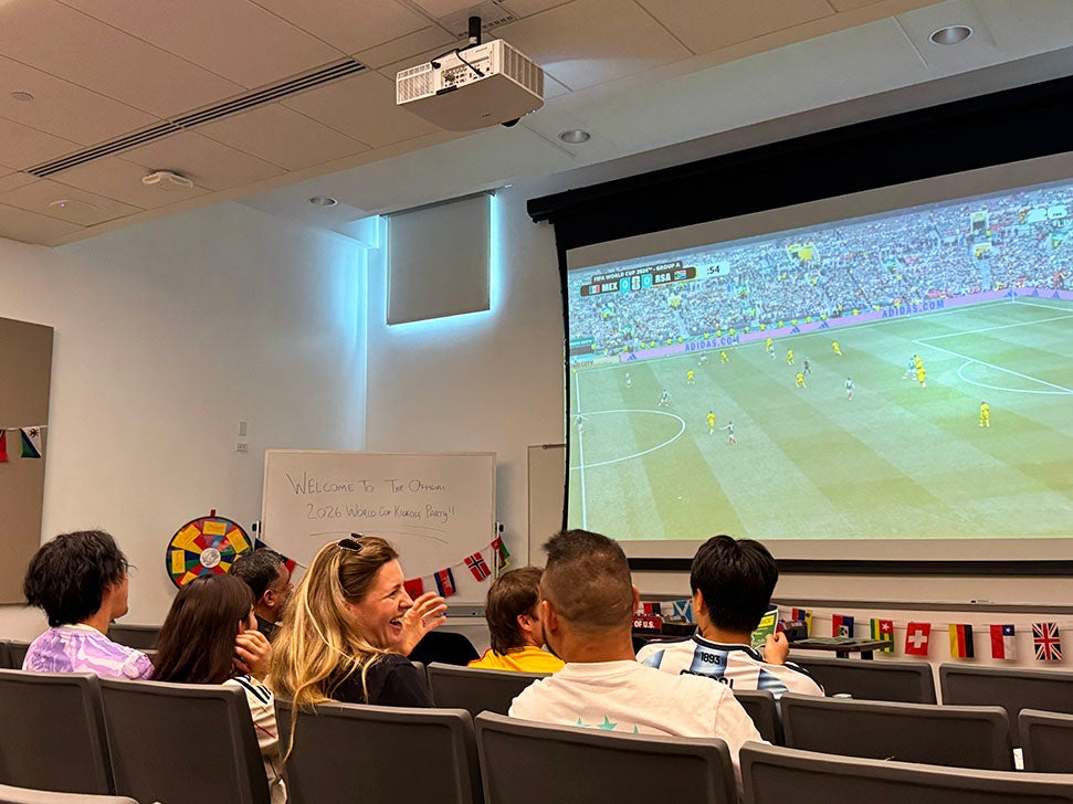 adults sitting in a lecture hall watching the World Cup