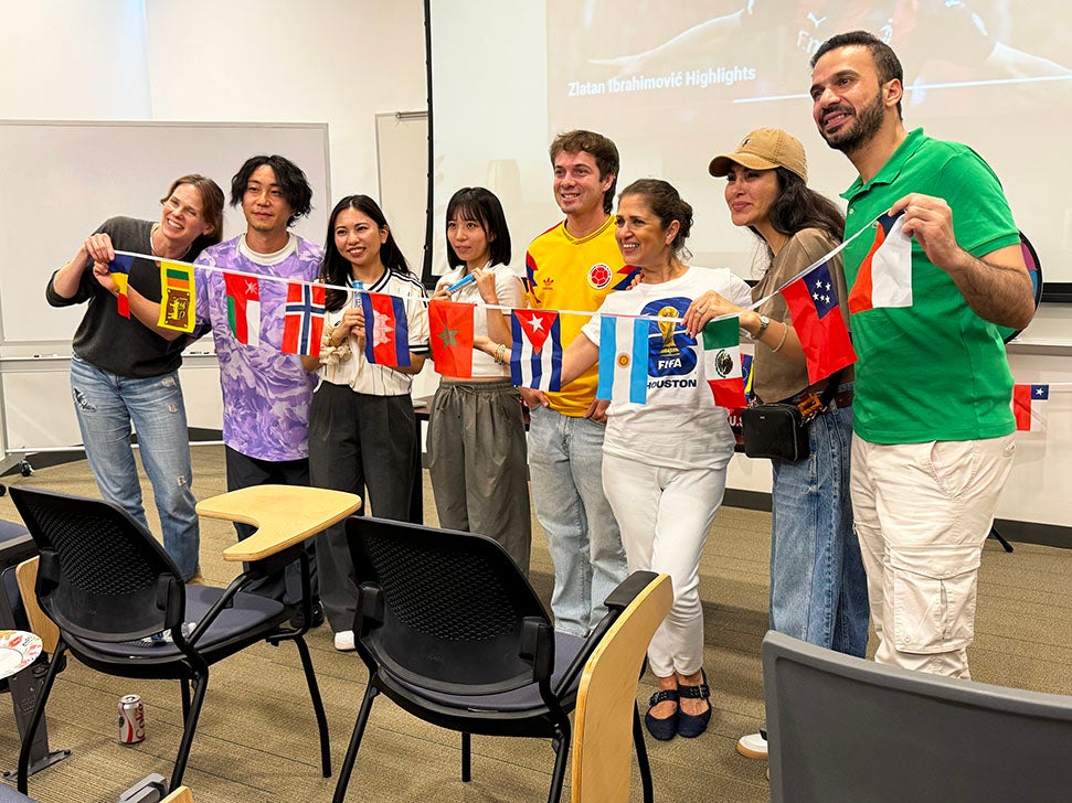 diverse group of college students holding banner with several world flags