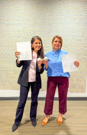 two teachers holding crossword puzzles and smiling