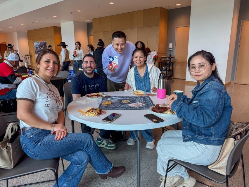 diverse group of adult students eating barbecue lunch around a table