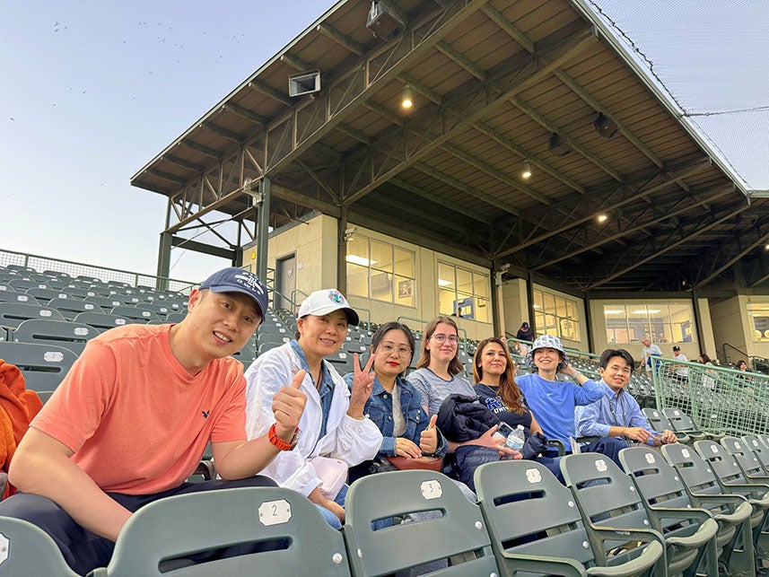adult international students sitting in the stands watching a baseball game