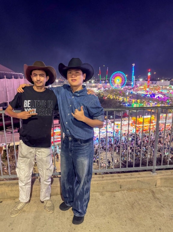two college-aged men posing in front of rodeo carnival