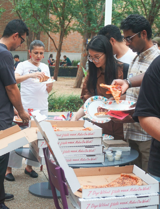 adult students eating pizza outside