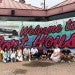 group of adults and small children standing in front of Welcome to Houston painting